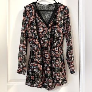 BCBG black and floral printed romper with lace detail and long sleeve in size XS